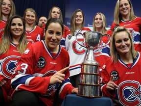 Members of Les Canadiennes, including Caroline Ouellette, front left, and Marie-Philip Poulin, front right gather around the Clarkson Cup at the Bell Sports Complex in Brossard on Wednesday, March 8, 2017 during news conference following  their win of the Clarkson Cup on Sunday.