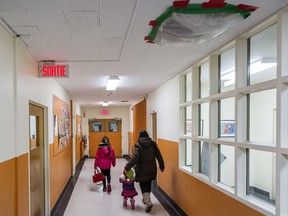 A parent arrives with children for a public meeting at the Sainte-Catherine-de-Sienne school in the borough of Notre-Dame-de-Grâce in Montreal on Thursday, Nov. 20, 2014. The school, which is part of the Commission scolaire de Montreal school board, had to close and will be renovated.