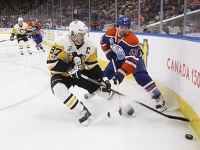 Pittsburgh Penguins' Sidney Crosby  and Edmonton Oilers' David Desharnais battle for the puck during second period NHL action in Edmonton on Friday, March 10, 2017.