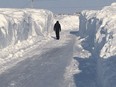 Churchill, Man., was covered with 60 cm of snow over three days, prompting the town authorities to declare a local state of emergency on Friday. A person walks down a plowed street, surrounded by snow walls, in Churchill, Man., in a Saturday, March 11, 2017, handout photo.