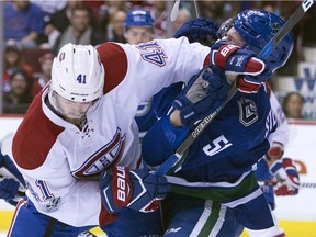 Canucks defenceman Troy Stecher fights for control of the puck with Canadiens' Paul Byron Tuesday night in Vancouver.