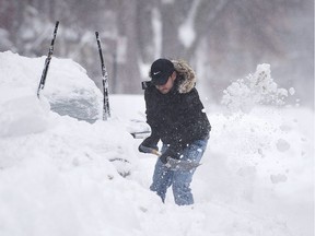 A man shovels snow from around his car following a winter storm in Montreal, Wednesday, March 15, 2017.