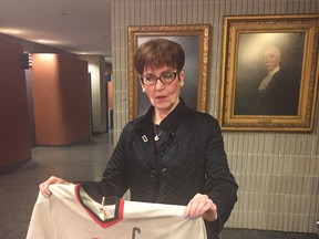 Ruth Ellis holds the hockey sweater her son Doug wore when he was 11 years old.