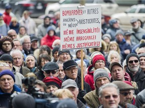 People hold up signs during a demonstration outside Bombardier's head office in Montreal, Sunday, April 2, 2017, to protest recent pay hikes and bonuses to the company's top executives.