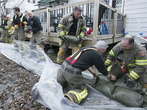 Pincourt firefighters use sandbags as a precautionary measure, to shore-up land from the rising waters of the Ottawa river around homes located on Chemin Duhamel in Pincourt on Monday April 17, 2017.