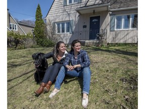 Terri Rindress (left) and Anita Trudel sit with their dog Shelby on the front lawn of their newly-purchased home in Pointe-Claire.