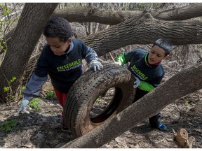 Airee Fraser, 8, left, and Roland Balog, 11, right, wheel a car tire off the hill at the annual clean-up held by Sauvons la falaise held the Saint-Jacques Escarpment in Montreal Saturday.