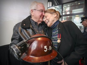 Dr. Geneviève de Groot leans into retired firefighter Léo Boulanger following a ceremony to honour the 143 Montreal firefighters who have been killed in the line of duty in Montreal Monday April 3, 2017.  Dr. de Groot wore the helmet Boulanger is holding when she donned firefighters clothing to help rescue firefighters trapped in the collapsed building of the Woodhouse furniture store fire in 1963.  Boulanger was one of the firefighters who worked on that fire.
