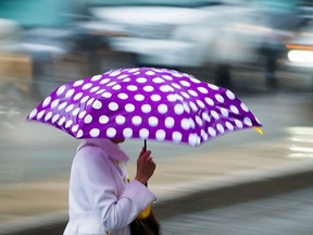 A woman crosses Ste-Catherine St. with an umbrella.