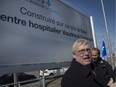 Quebec Health Minister Gaetan Barrette stands in front of the sign announcing a planned new hospital to serve the Vaudreuil-Soulanges region on April 4, 2016.