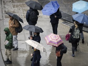 Commuters take shelter under umbrellas in Montreal Tuesday April 4, 2017.