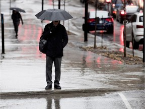 A pedestrian waits for a traffic light light during a rain fall in Montreal on Thursday April 6, 2017.