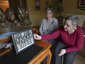 Cécile Dionne (right), with her sister Annette (they are the two surviving Dionne quintuplets, born in Ontario in 1934), with a photo of themselves and their sisters when they were children.