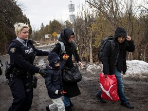 A family of three is escorted to a police vehicle by a Royal Canadian Mounted Police officer after they crossed the U.S.-Canada border into Canada, February 23, 2017 in Hemmingford, Quebec.