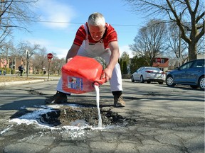 Councillor Jeremy Searle pours water-soluble white paint around a pothole on Fielding Ave. on Thursday.