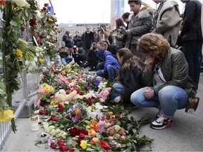 People lay down flowers at a fence near the department store where a truck rammed into pedestrians in central Stockholm, Sweden, Saturday, April 8, 2017.