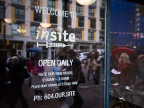 People are reflected in the window of supervised injection site, Insite, during a demonstration calling for more safe injection sites, in the Downtown Eastside of Vancouver, B.C., on Wednesday June 8, 2016. Safe injection sites help reduce the spread of infectious illness.