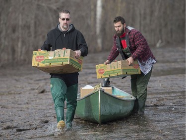 Two men remove boxes from a canoe on a street in the town of Rigaud, Que., Thursday, April 20, 2017, following flooding in the area. A state of emergency has been issued for the town.