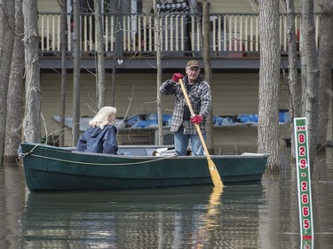 A man and woman use a boat to move along a street in the town of Rigaud, Que., west of Montreal, Thursday, April 20, 2017, following flooding in the area. A state of emergency has been issued for the town.