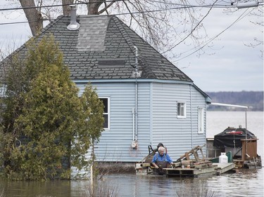 A man wades through water next to his house close to the town of Rigaud, Que., Thursday, April 20, 2017, following flooding in the area. A state of emergency has been issued for the town.