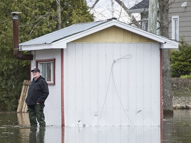 A man stands in his yard in the town of Rigaud, Que., west of Montreal, Thursday, April 20, 2017, following flooding in the area. A state of emergency has been issued for the town.