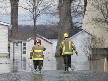 Members of the Rigaud's emergency services wade through water on a street in the town on Thursday, April 20, 2017.