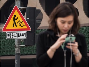 A sign advising pedestrians of the dangers of using smartphones while walking is displayed at an intersection in central Seoul on June 22, 2016.