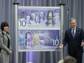 Governor of the Bank of Canada Stephen Poloz, right, and Parliamentary Secretary to the Minister of Finance Ginette Petitpas Taylor look on after the unveiling of the Canada 150 commemorative bank note in Ottawa on Friday, April 7, 2017.