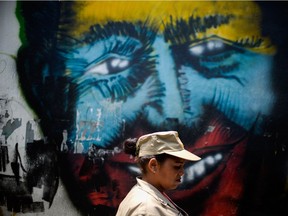 Photo of the day: A Bolivarian militia member walks by graffiti of the late Venezuelan President Hugo Chavez during a rally to commemorate 15 years of the coup that briefly removed him from power, in Caracas on April 11, 2017.