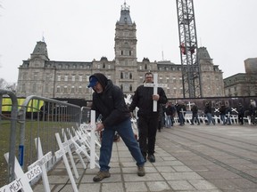 Union workers lay 217 crosses with names of workers who died at work in 2016, during a ceremony, Friday, April 28, 2017 in front the legislature in Quebec City.