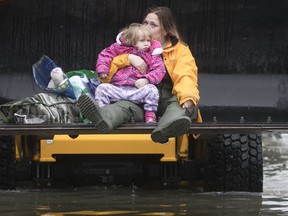 Two-year-old Olivia Kulisz and her mother Stephanie left their home via the bucket of a loader in Île Bizard May 6, 2017.