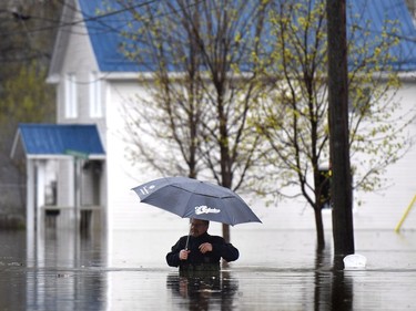 A man is up to the top of his chest waders as he walks along a flooded residential street in Gatineau, Que., as rising river levels and heavy rains continue to cause flooding, on Saturday, May 6, 2017.