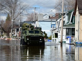 A military vehicle drives along a flooded street as waters breach the Gatineau River and flood the neighbourhood in Gatineau, Quebec on Wednesday, May 10, 2017.