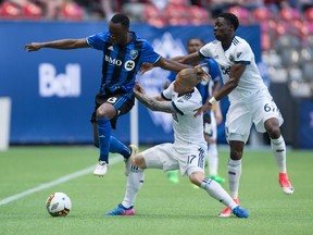 Montreal Impact's Ballou Tabla, left, leaps past Vancouver Whitecaps' Marcel de Jong, centre, as he and Alphonso Davies attempt to stop him during first-half semifinal Canadian Championship soccer action in Vancouver, B.C., on Tuesday May 23, 2017.