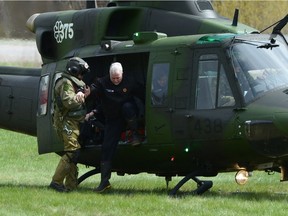 Quebec Premier Philippe Couillard (centre) arrives in a helicopter to tour flood-affected areas of the province in Luskville, Que., Monday, May 8, 2017.