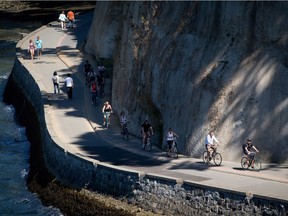 Vancouverites are increasing getting around on foot or two wheels. Here, cyclists ride along the Stanley Park seawall, as pedestrians take a stroll.