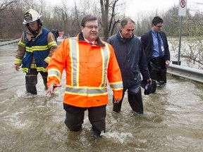 In this file photo from May, 2017 Montreal Mayor Denis Coderre walks through the flooded streets of the Île-Mercier district of Île-Bizard, Que.