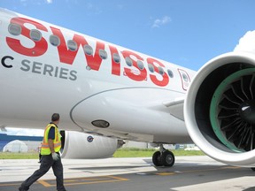 A maintenance crew member walks past a Bombardier CS100.