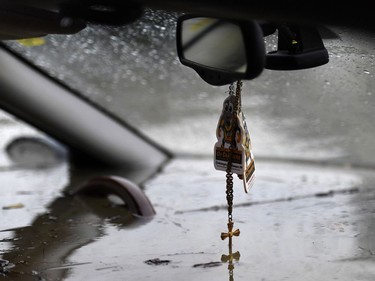 Floodwaters touch the bottom of a crucifix hanging from the rear view mirror of a car abandoned on a residential street in Gatineau, Que., as rising river levels and heavy rains continue to cause flooding, on Saturday, May 6, 2017.
