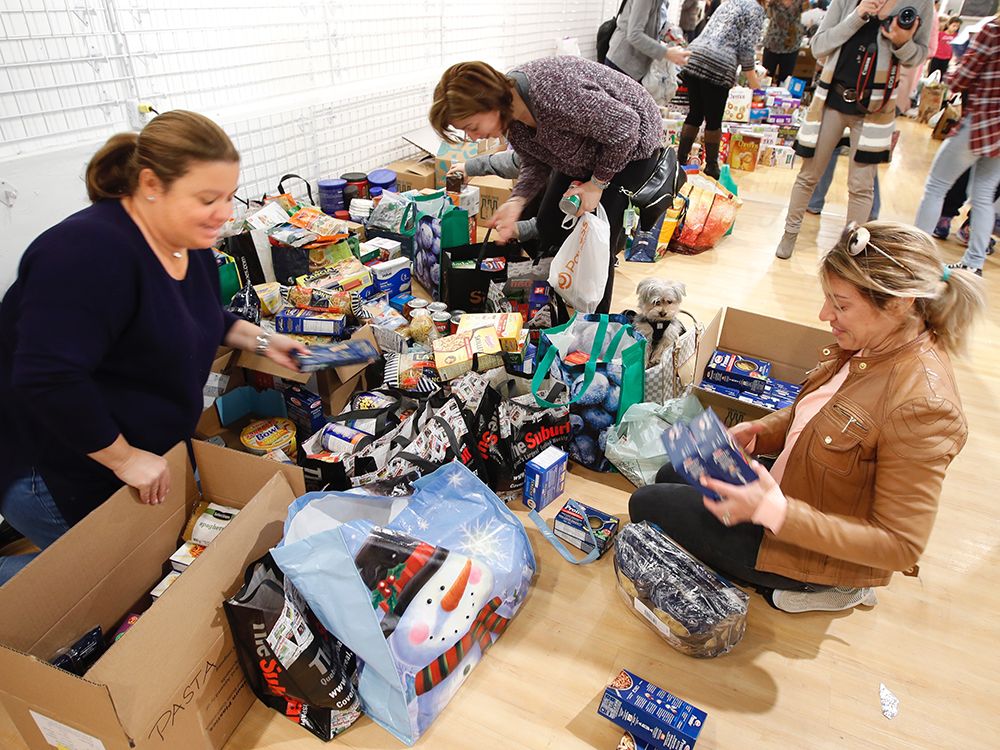 Volunteers kneel on the floor of an empty shop at Fairview Pointe Claire dividing food by food type during a food drive for flood victims.