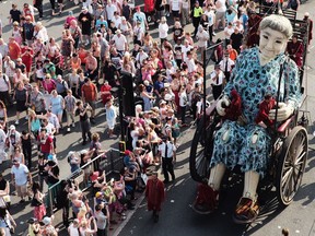 Crowds watch and follow the Giant Grandmother, one of the giant Royal De Luxe street puppets taking part in Liverpool's World War I centenary commemorations, as she walks through the streets of Liverpool on July 25, 2014 in Liverpool, England.
