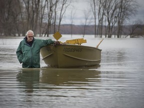 A resident walks his boat out of a flooded area by the overflowing Ottawa River in Rigaud April 22, 2017.