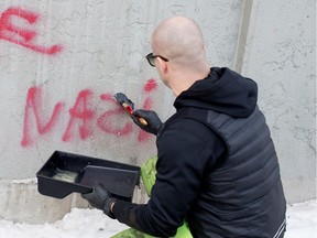 Corey Fleischer removes the word NAZI from a concrete wall in Montreal in 2015. Anti-Semitism in Quebec is down slightly in 2017, B'nai Brith says.