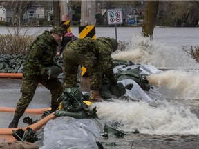 Firefighters and army personnel reinforce makeshift dikes along Lalande St. in Pierrefonds—Roxboro on Wednesday.