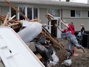 Lynn Eaton-Jones carries water soaked wood to a huge pile of debris as she helps a friend gut the basement of a flooded home on Des Maçons Street in Pierrefonds on Saturday, May 13, 2017.