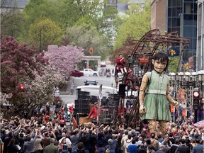 A crowd gathers to watch a huge puppet makes its way down McGill-College Ave. in Montreal on Friday May 19, 2017.