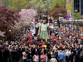 A crowd gathers to watch a huge puppet makes its way down McGill-College Ave. in Montreal on Friday May 19, 2017.