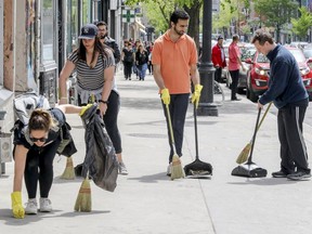 Helene Desbiens, left, Audrée Archambault, Gabriel Ducharme and Frederic Savard sweep up litter during the third edition of the Grand Corvé du Boulevard St-Laurent in Montreal on Sunday May 21, 2017.