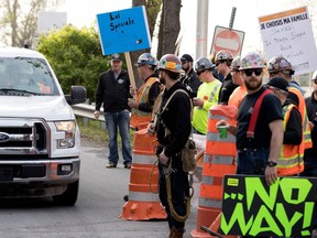 Constructions workers open the picket line to allow a security truck to cross the line at the Champlain Bridge construction site after they walked off the job in Montreal on May 24, 2017.