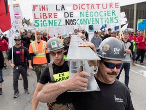 Members of the Iron Workers carry a steel beam as striking construction workers march through the streets of Montreal during Day 2 of a Quebec-wide strike May 25, 2017.